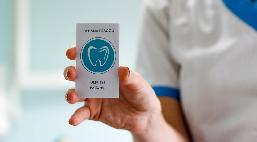 Εικόνα της Τατιάνας Φράγκου (οδοντίατρου) κρατώντας την επαγγελματική της κάρτα.